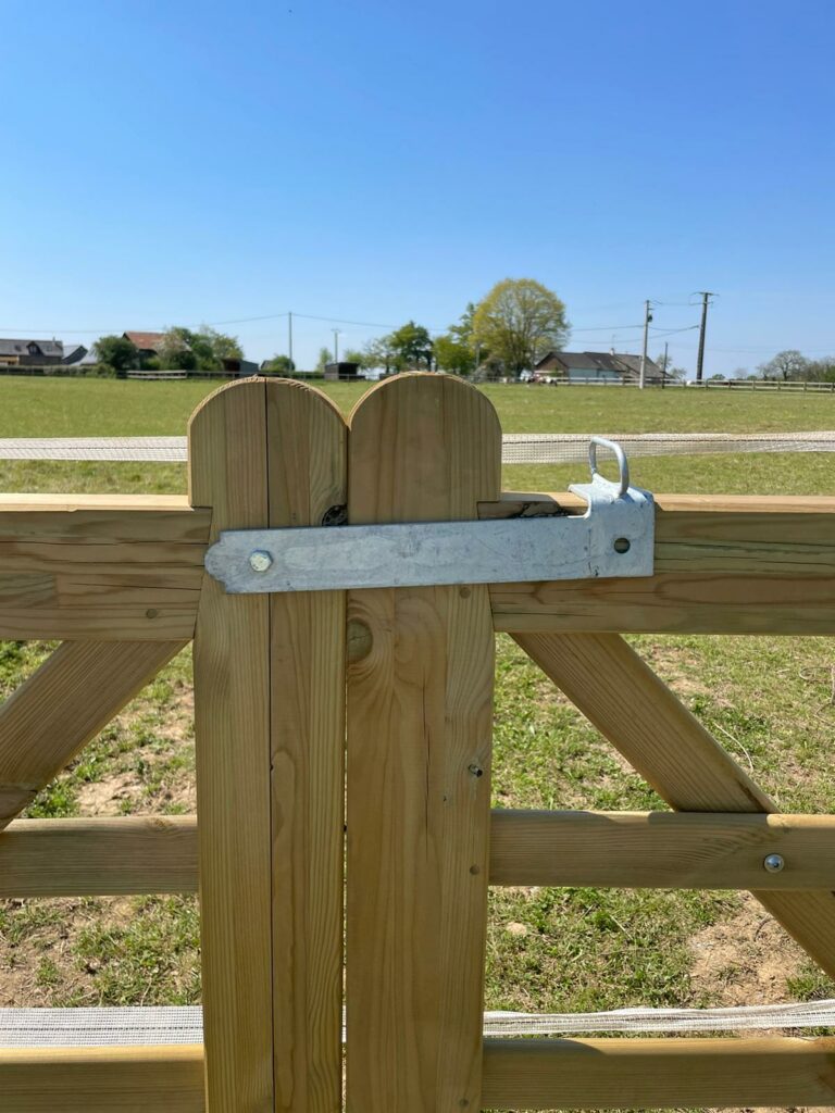 Verrou à bascule installé sur barrière double en bois