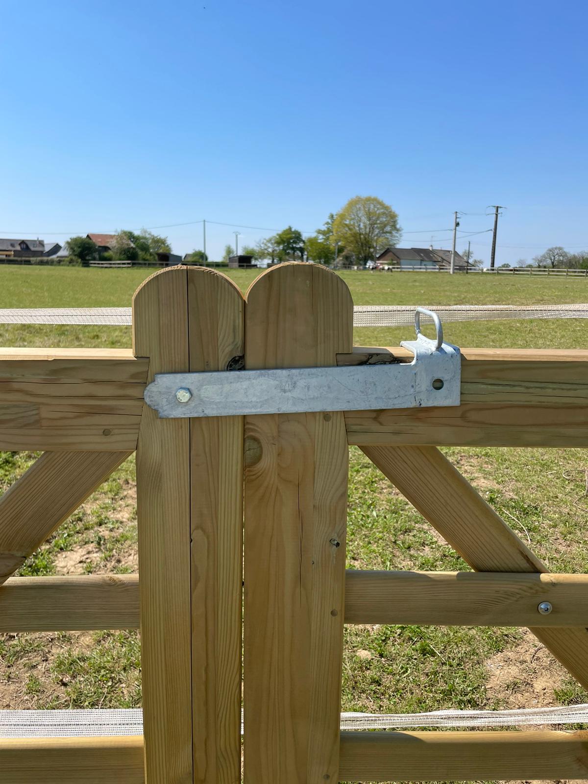 Verrou à bascule installé sur barrière double en bois